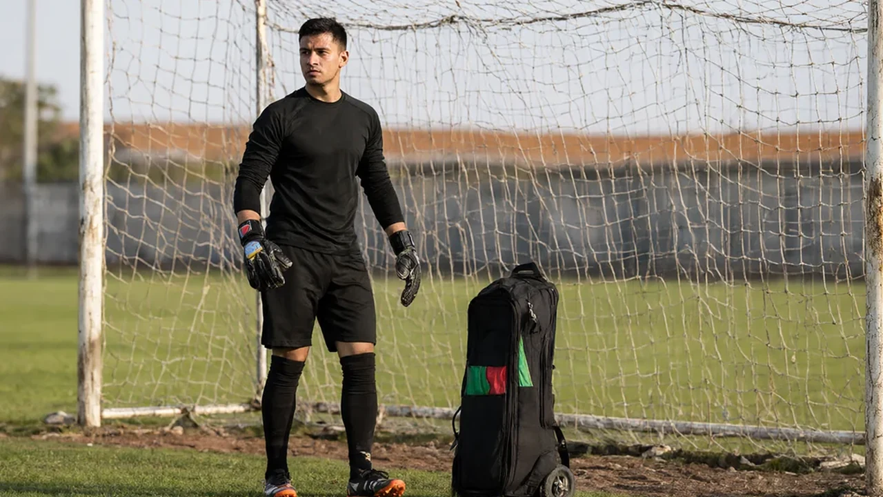 Open sports bag with goalkeeper gloves towel and tape on a bench